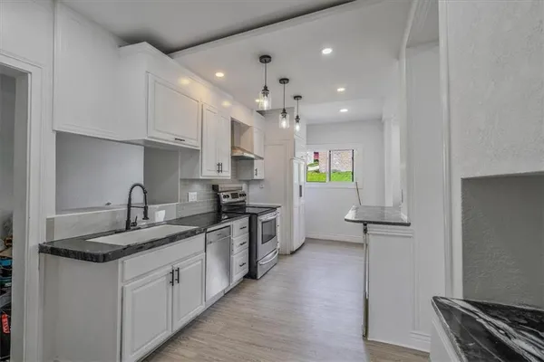a kitchen with kitchen island granite countertop a sink cabinets and wooden floor