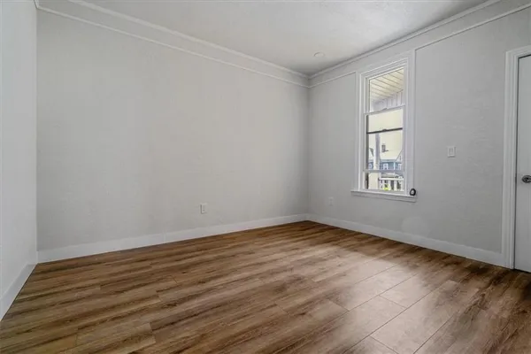 a view of an empty room with wooden floor and a window