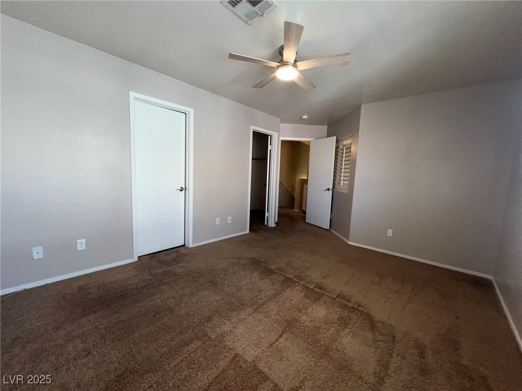 8028 Desire Drive Las Vegas, NV 89128 - Photo 12 of 15 Unfurnished bedroom featuring dark carpet, a spacious closet, and ceiling fan