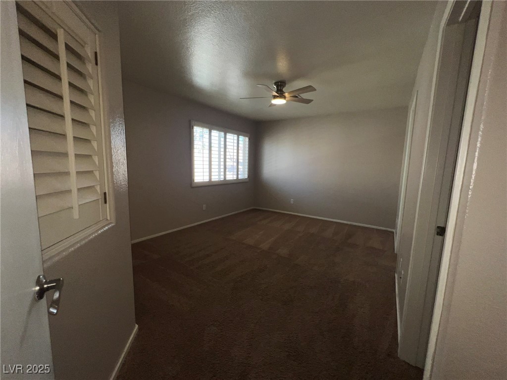 8028 Desire Drive Las Vegas, NV 89128 - Photo 10 of 15 Unfurnished room with a textured ceiling, dark colored carpet, and ceiling fan