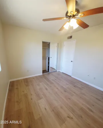 an empty room with wooden floor fan and windows