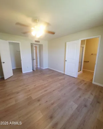 a view of an empty room with window and chandelier fan