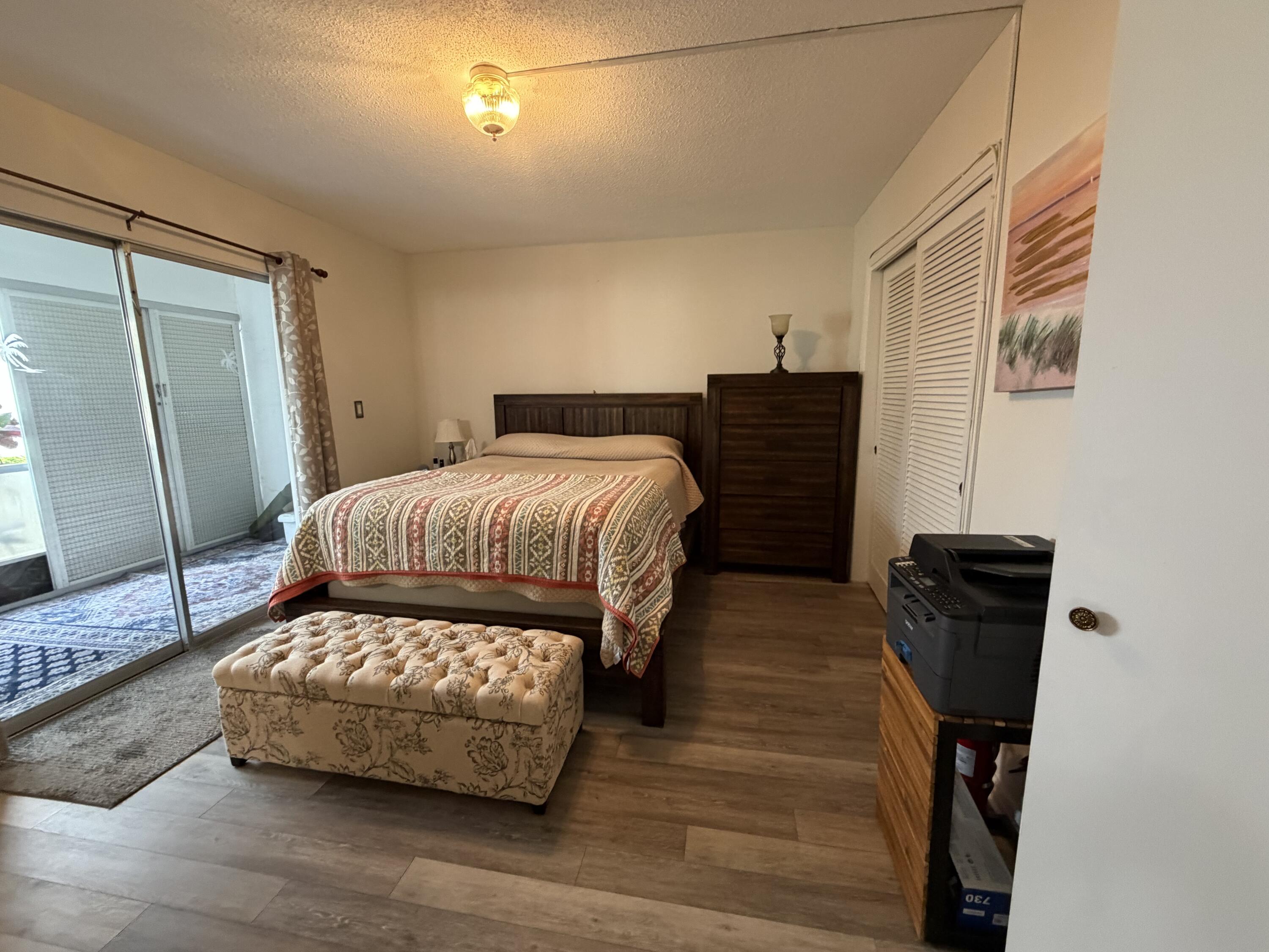 2050 Northeast 39th Street, Unit S103 Lighthouse Point, FL 33064 - Photo 13 of 46 a bedroom with a bed and wooden floor