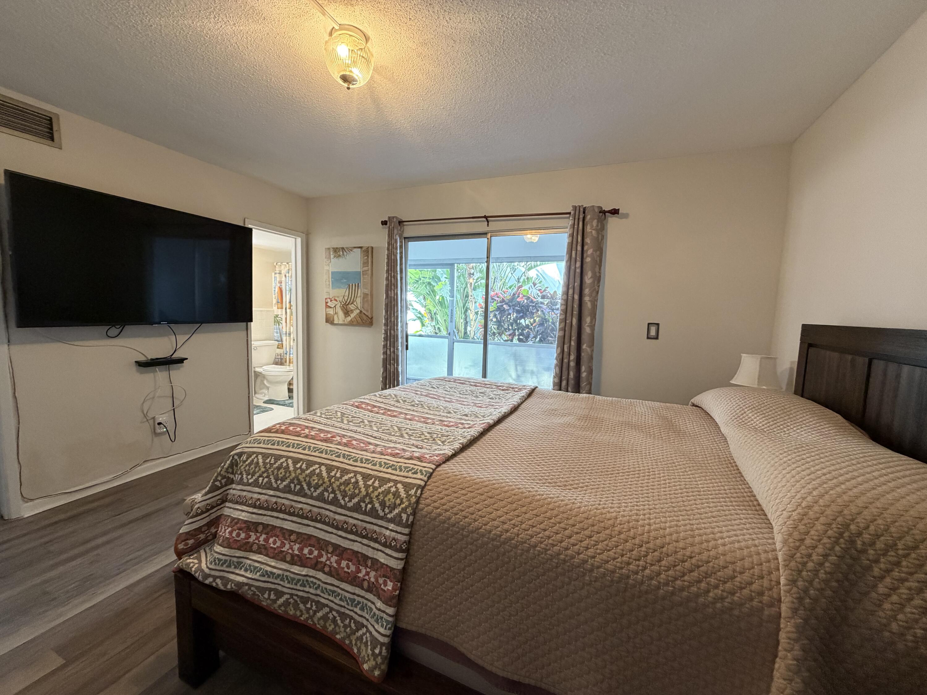 2050 Northeast 39th Street, Unit S103 Lighthouse Point, FL 33064 - Photo 16 of 46 a bedroom with a bed and a flat screen tv