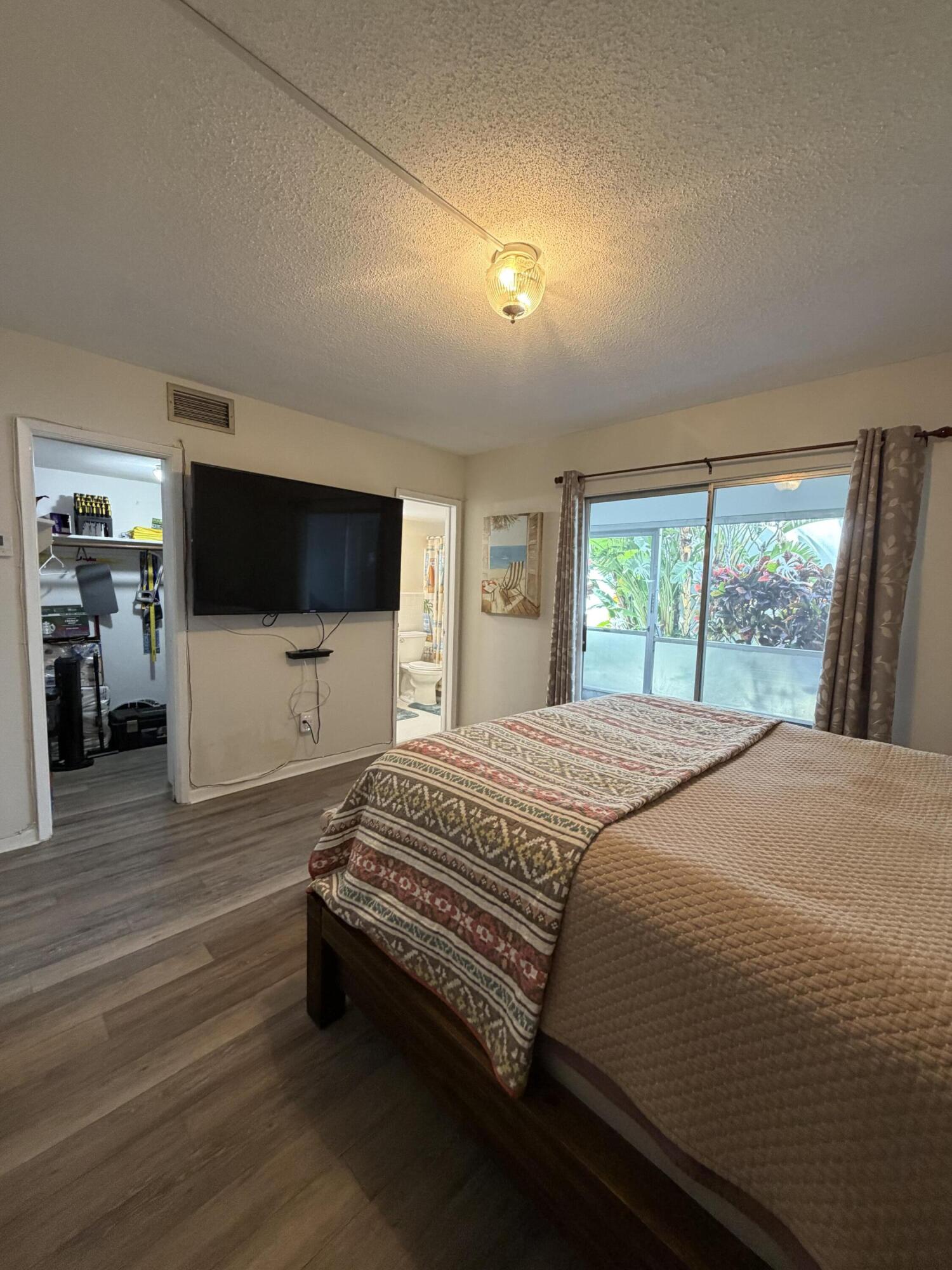 2050 Northeast 39th Street, Unit S103 Lighthouse Point, FL 33064 - Photo 17 of 46 a spacious bedroom with a bed and a flat screen tv