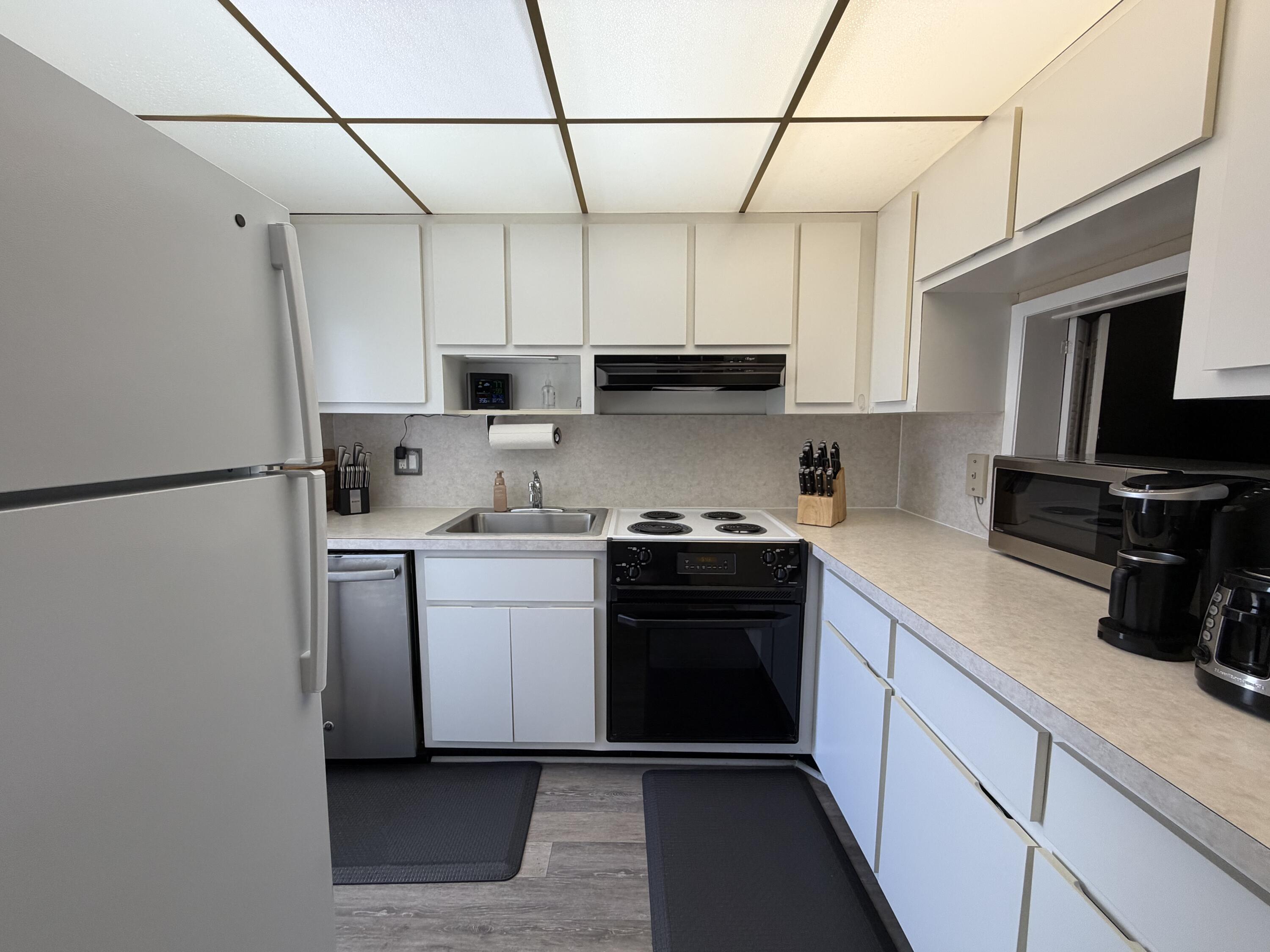 2050 Northeast 39th Street, Unit S103 Lighthouse Point, FL 33064 - Photo 25 of 46 a kitchen with stainless steel appliances granite countertop a sink stove and refrigerator