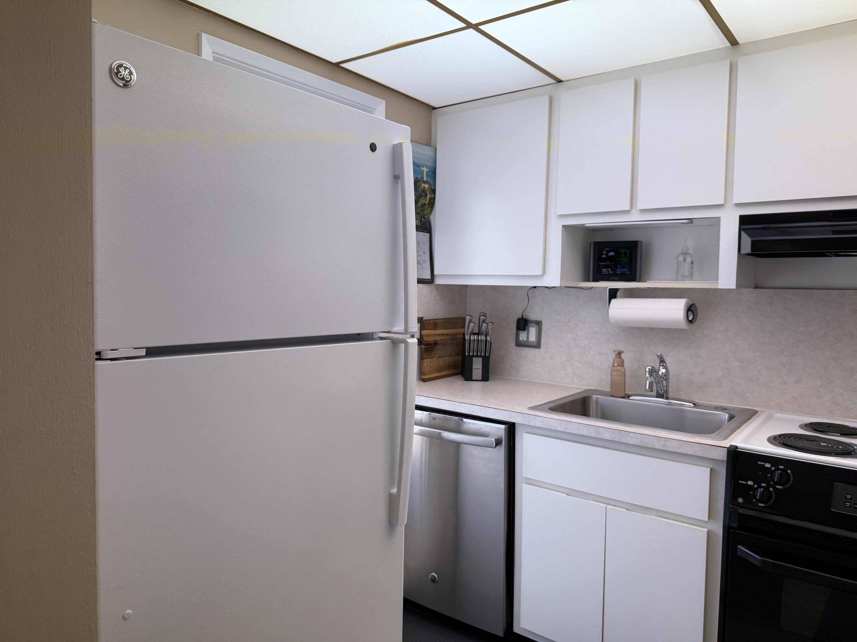 2050 Northeast 39th Street, Unit S103 Lighthouse Point, FL 33064 - Photo 27 of 46 a kitchen with stainless steel appliances a refrigerator sink and cabinets