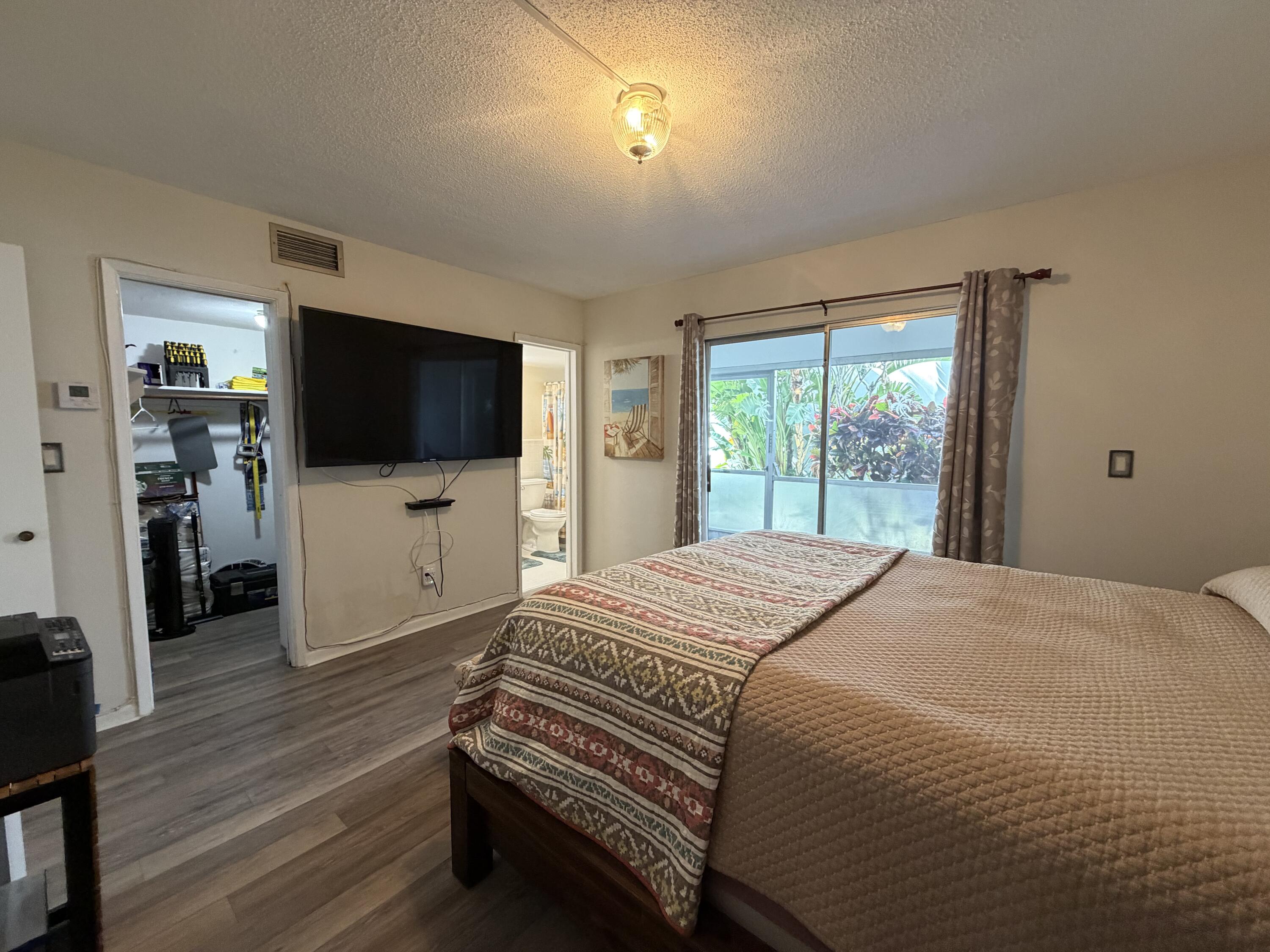 2050 Northeast 39th Street, Unit S103 Lighthouse Point, FL 33064 - Photo 33 of 46 a bedroom with a bed and a flat screen tv