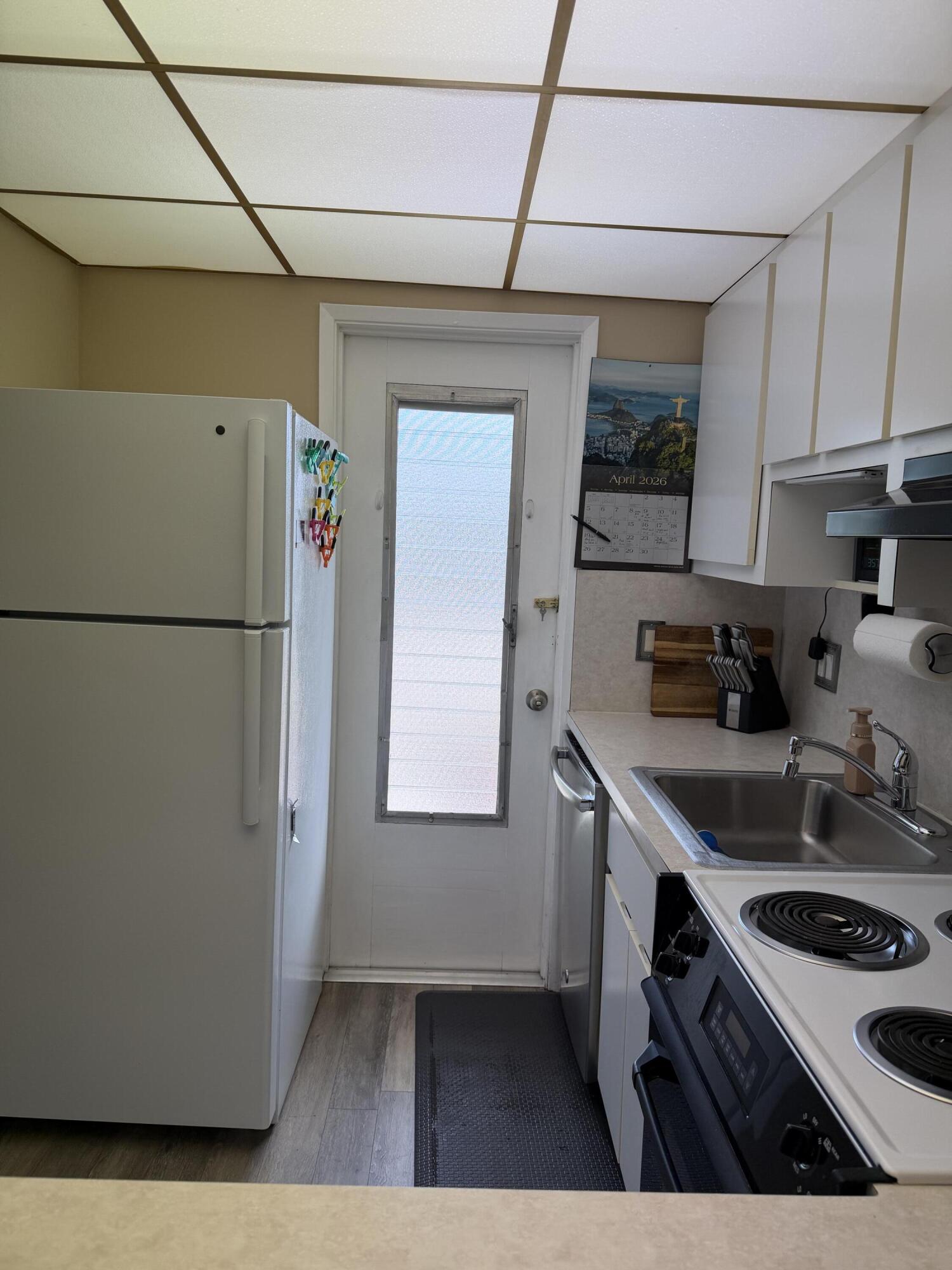 2050 Northeast 39th Street, Unit S103 Lighthouse Point, FL 33064 - Photo 42 of 46 a kitchen with a sink a refrigerator and white cabinets