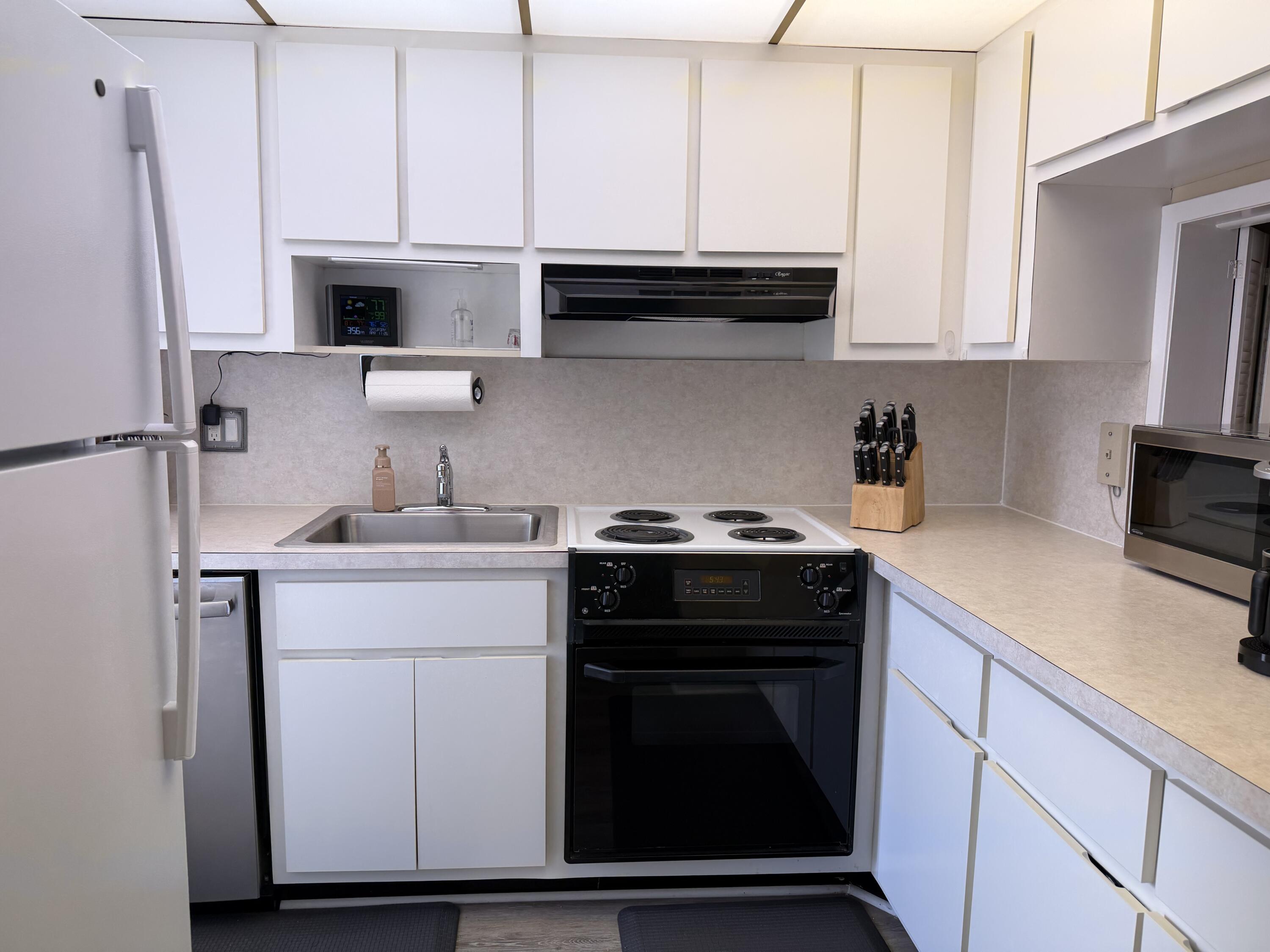 2050 Northeast 39th Street, Unit S103 Lighthouse Point, FL 33064 - Photo 43 of 46 a kitchen with stainless steel appliances white cabinets and a stove