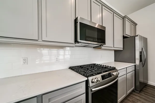 a kitchen with kitchen island a sink a stove a refrigerator and white cabinets