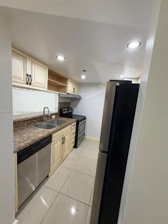 a kitchen with granite countertop stainless steel appliances a sink and a refrigerator