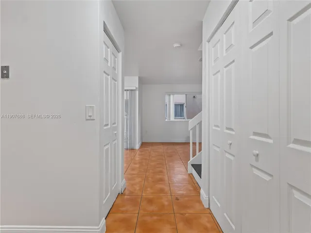 a view of a hallway with white walls and wooden floor