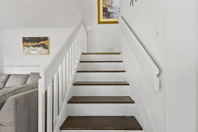 a view of staircase with white walls and a rug
