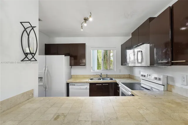 a kitchen with stainless steel appliances a sink a stove a refrigerator cabinets and a window