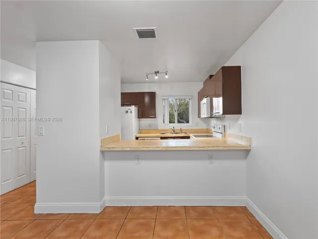a view of a kitchen with kitchen island a sink appliances and a counter space