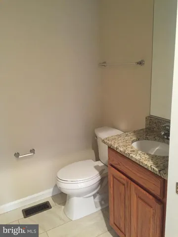 a bathroom with a granite countertop toilet and a sink