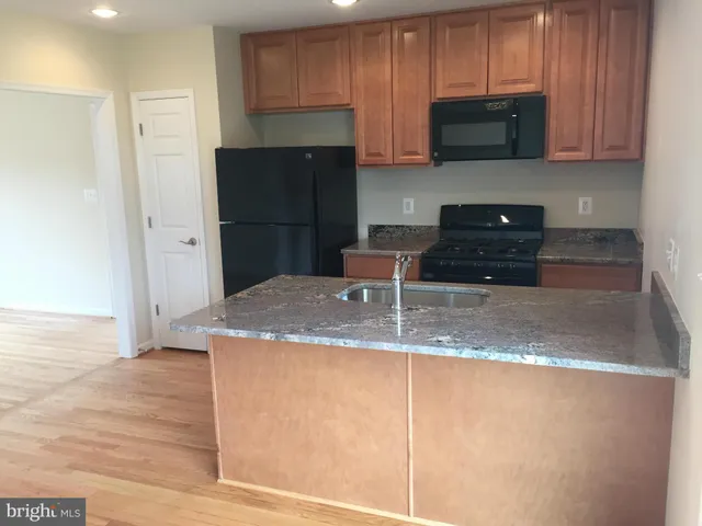 a kitchen with stainless steel appliances granite countertop a refrigerator a stove a sink and a microwave