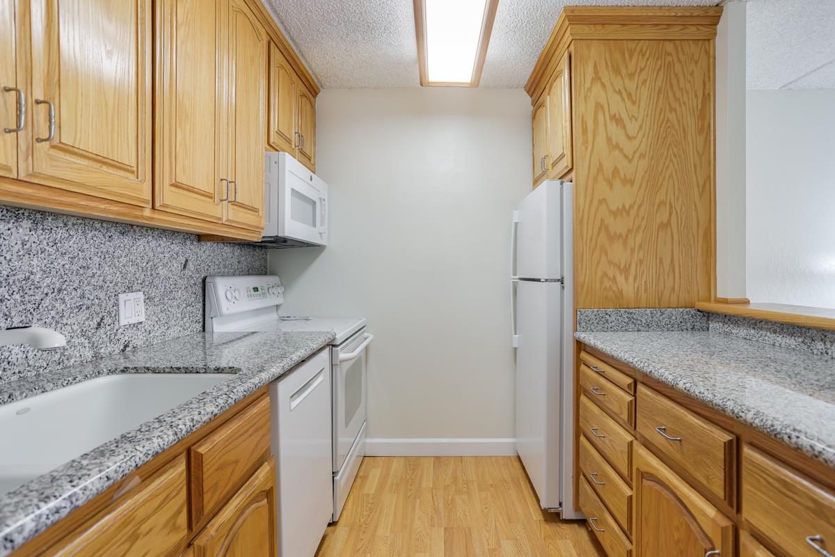 1700 Civic Center Drive, Unit 214 Santa Clara, CA 95050 - Photo 6 of 17 a kitchen with granite countertop cabinets stainless steel appliances a sink and wooden floor