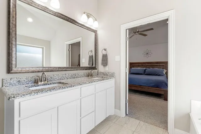 a en suite bathroom with a granite countertop sink and mirror