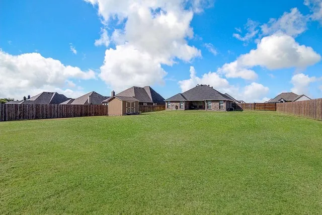 a view of a house with a big yard and large trees