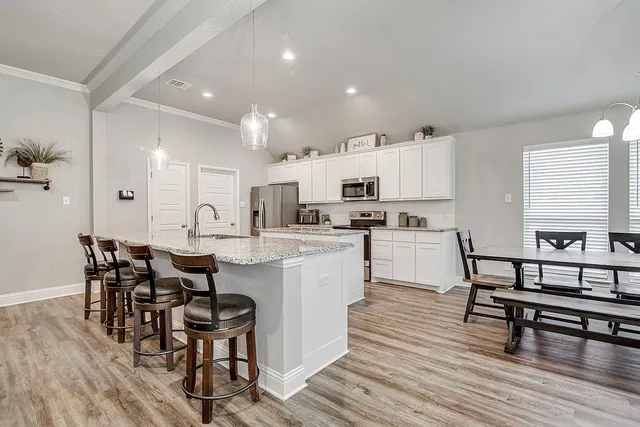 a kitchen with stainless steel appliances a dining table chairs and wooden floor