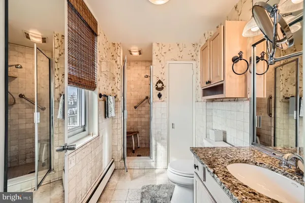 a bathroom with a granite countertop double vanity sink a mirror and a shower