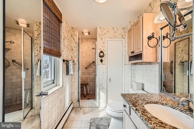 a bathroom with a granite countertop double vanity sink a mirror and a shower