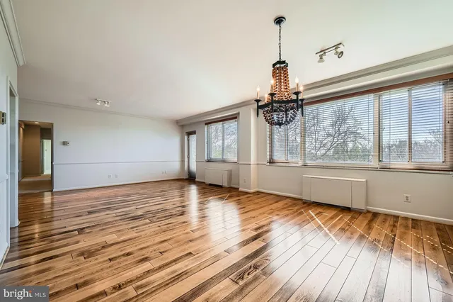 a view of empty room with wooden floor and fan