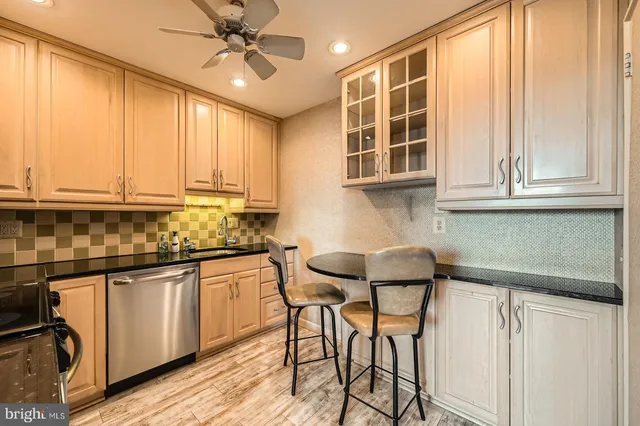 a kitchen with stainless steel appliances granite countertop white cabinets a microwave oven a sink and dishwasher with wooden floor