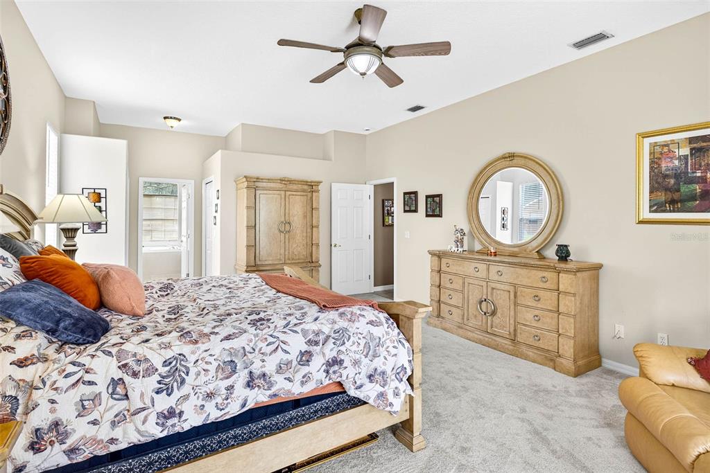 8518 West Knights Griffin Road Plant City, FL 33565 - Photo 39 of 74 a bedroom with a bed a mirror on dresser and a chandelier