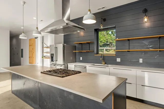 a kitchen with kitchen island a counter top a fireplace and a sink