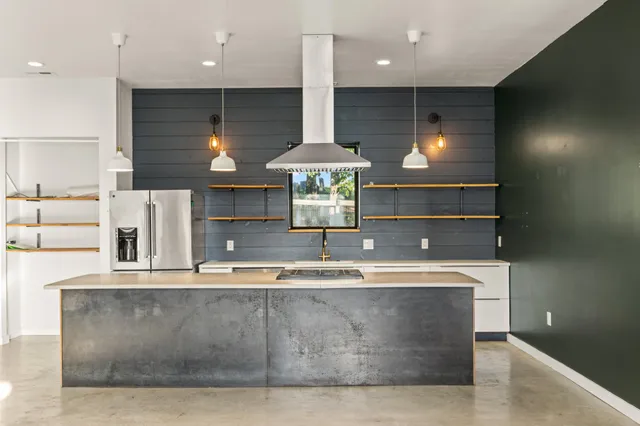 a large kitchen with stainless steel appliances a dining table chairs and a refrigerator