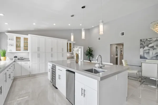 a large kitchen with a large counter top a sink a window and stainless steel appliances