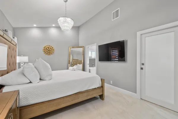 a bedroom with a large bed and a flat tv screen on dresser