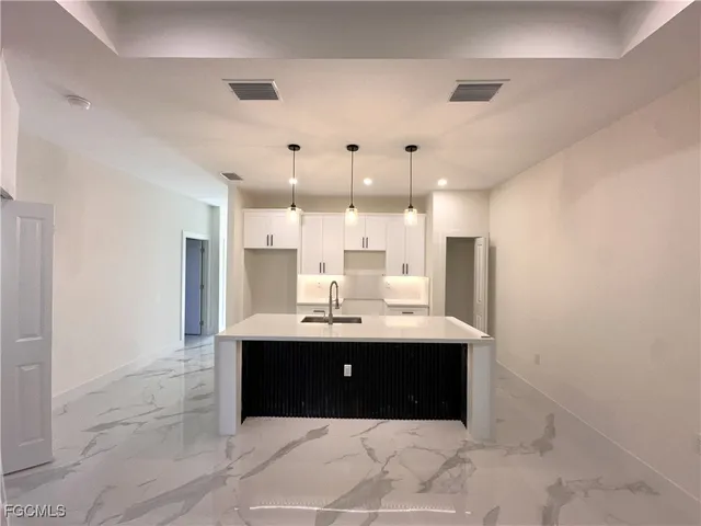 a view with kitchen island a sink wooden floor and a chandelier