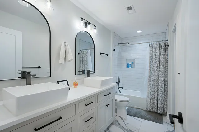 a bathroom with a double vanity sink toilet and shower
