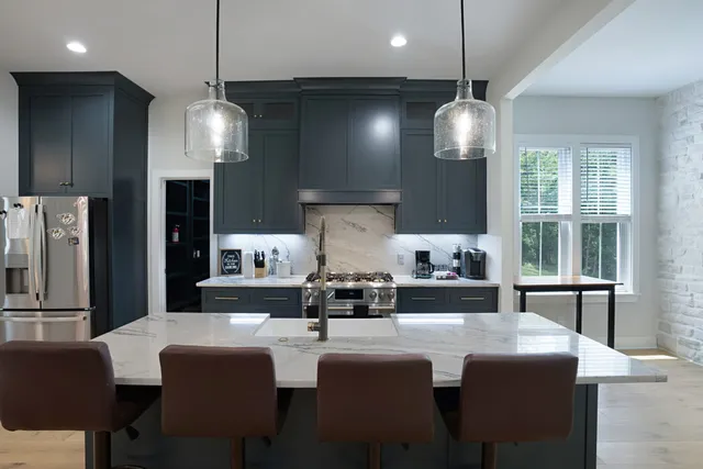 a large kitchen with a dining table chairs stainless steel appliances and cabinets