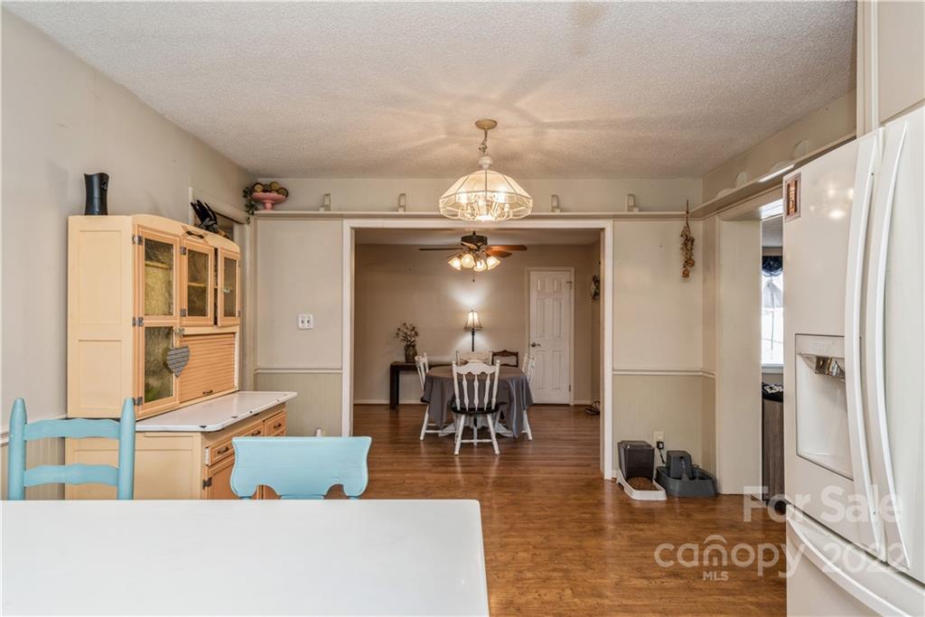 4600 Stallings Road Matthews, NC 28105 - Photo 15 of 38 a dining room with wooden floor a chandelier a wooden table and chairs