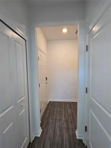 a view of a hallway with wooden floor and closet