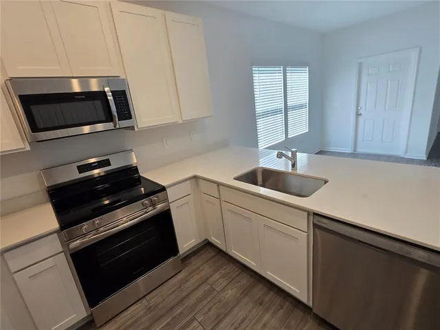 a kitchen with sink a microwave a stove and cabinets