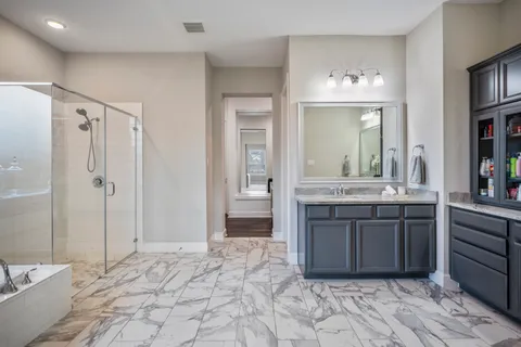 a spacious bathroom with a granite countertop sink a mirror and a bathtub