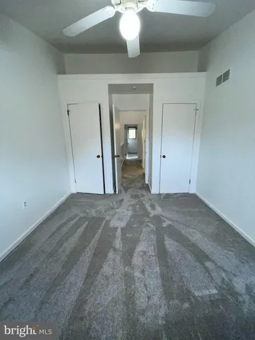 an empty room with a ceiling fan and window