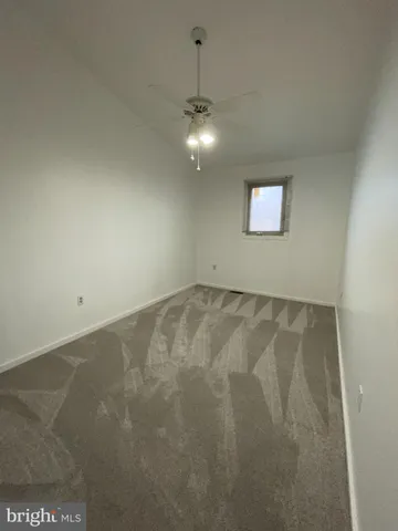 a view of an empty room with a chandelier fan