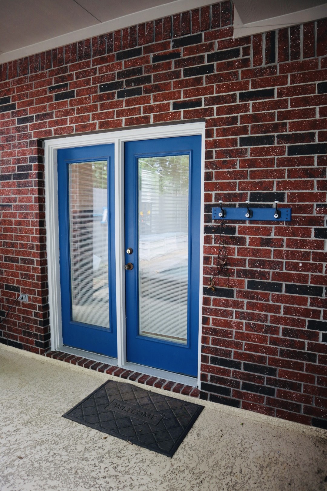 19114 Emory Trail Spring, TX 77388 - Photo 26 of 32 Great space for poolside breakfast with backdrop featuring a brick exterior with a set of vibrant blue double doors, complete with glass panels.