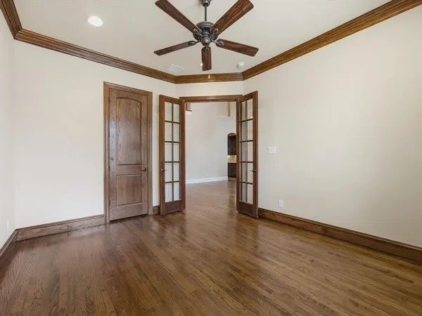 an empty room with wooden floor chandelier and windows