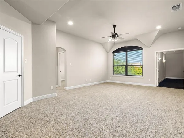 an empty room with windows and ceiling fan