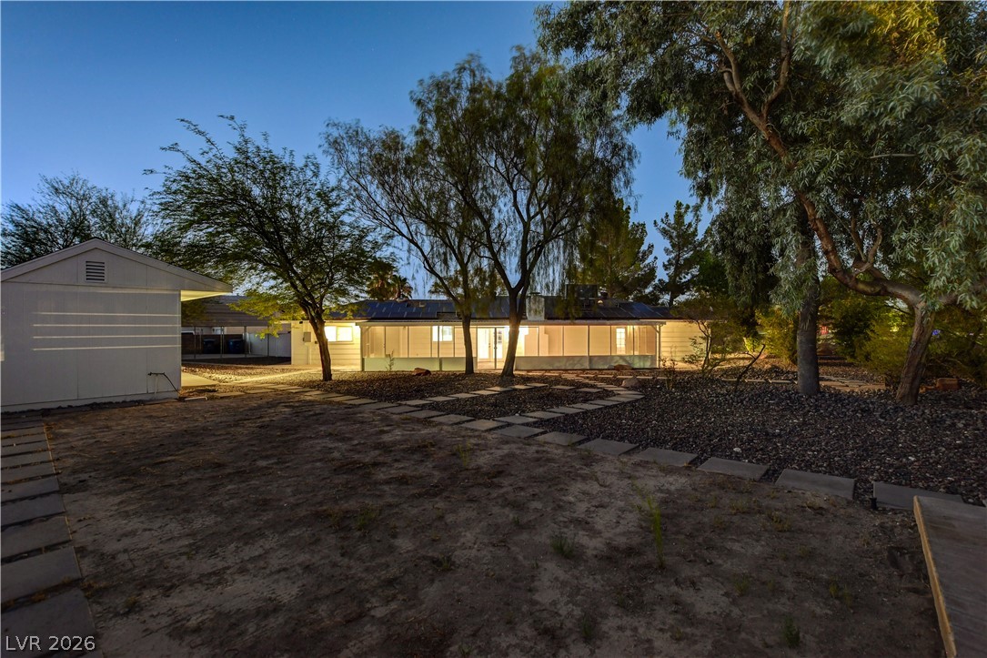 7631 Bermuda Road Las Vegas, NV 89123 - Photo 60 of 64 A tranquil evening view reveals a charming home illuminated amidst verdant trees and a structured pathway.