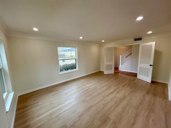 an empty room with wooden floor and windows