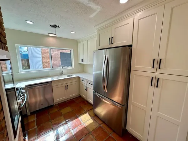 a large kitchen with stainless steel appliances granite countertop a refrigerator sink and cabinets